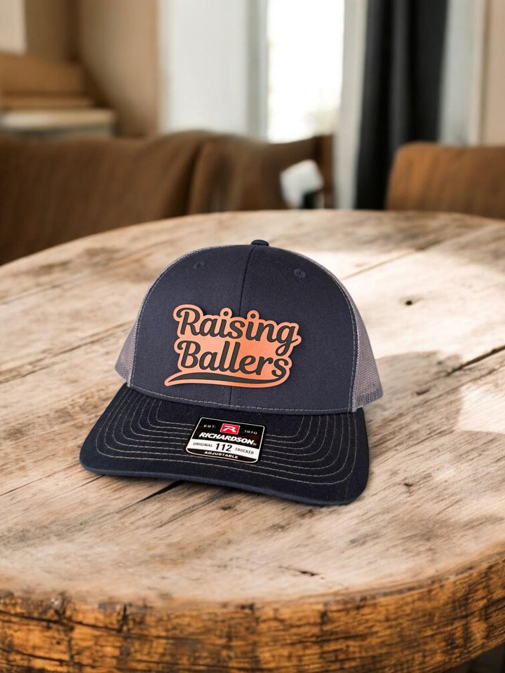 Raising Ballers baseball and football dad trucker hat by BubbleHead Ink