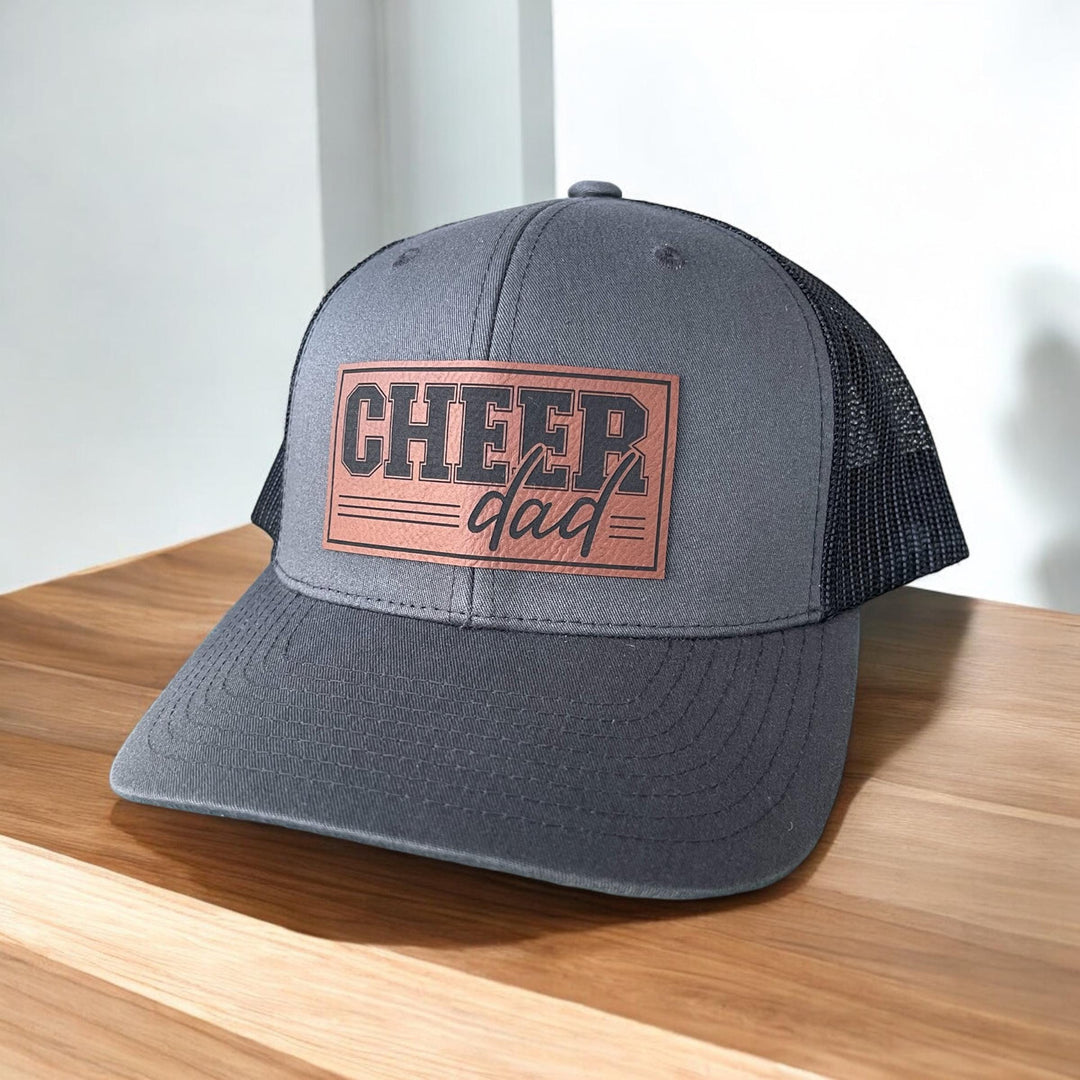 Adjustable Cheer Dad Trucker Hat with a comfortable fit and breathable black mesh back.  Made for proud dads at cheer events.